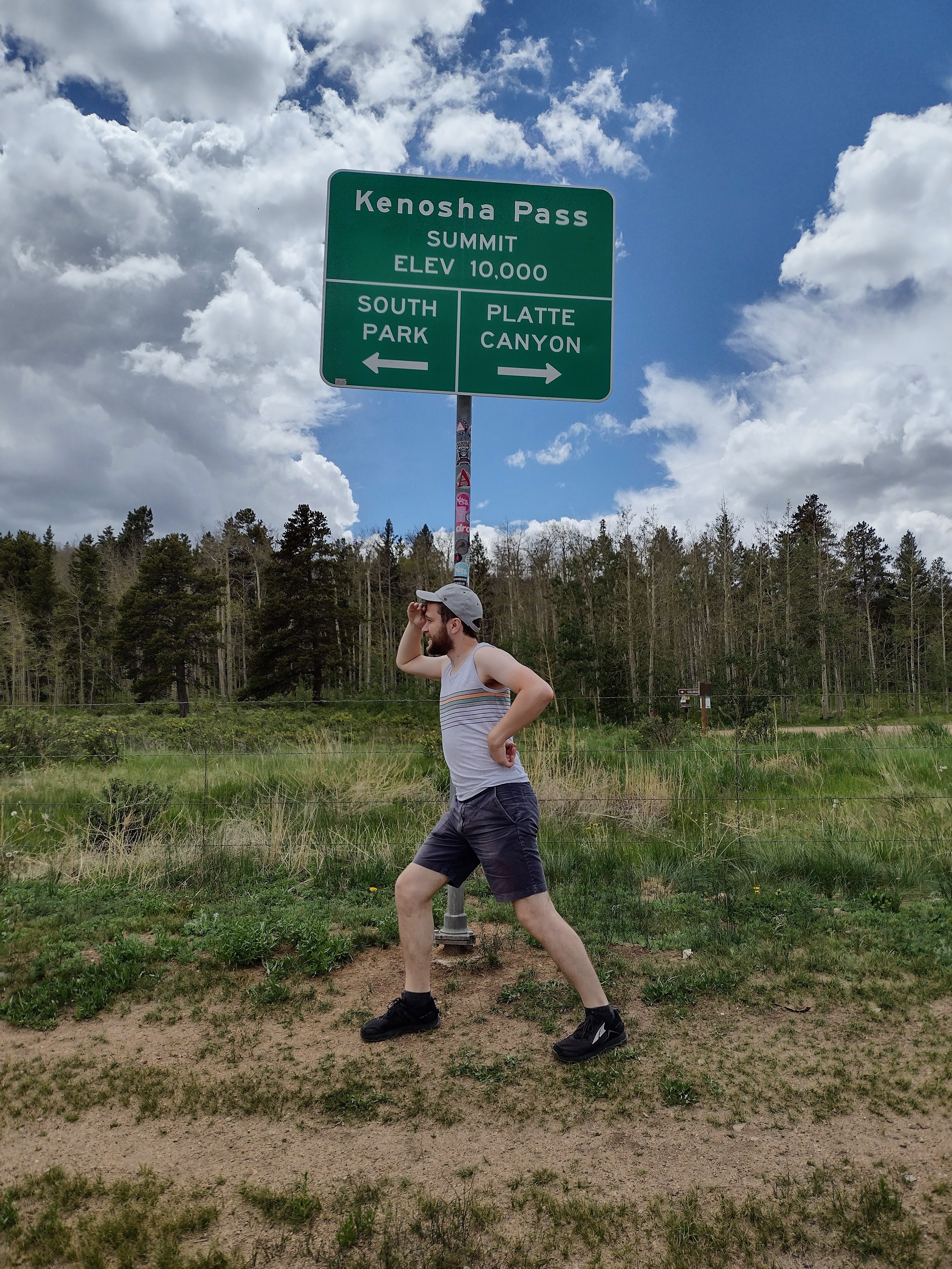 I stand in front of the sign for Kenosha Pass, elevation 10,000 ft, looking westward in a comical pose toward South Park, Colorado